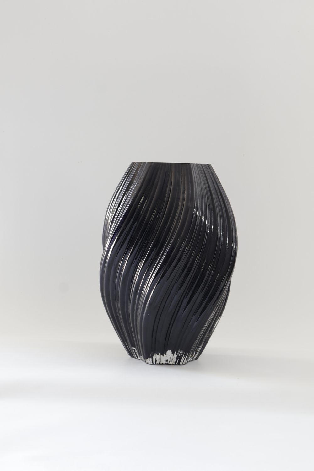 Dark black glass vase features a dynamic, twisted spiral design