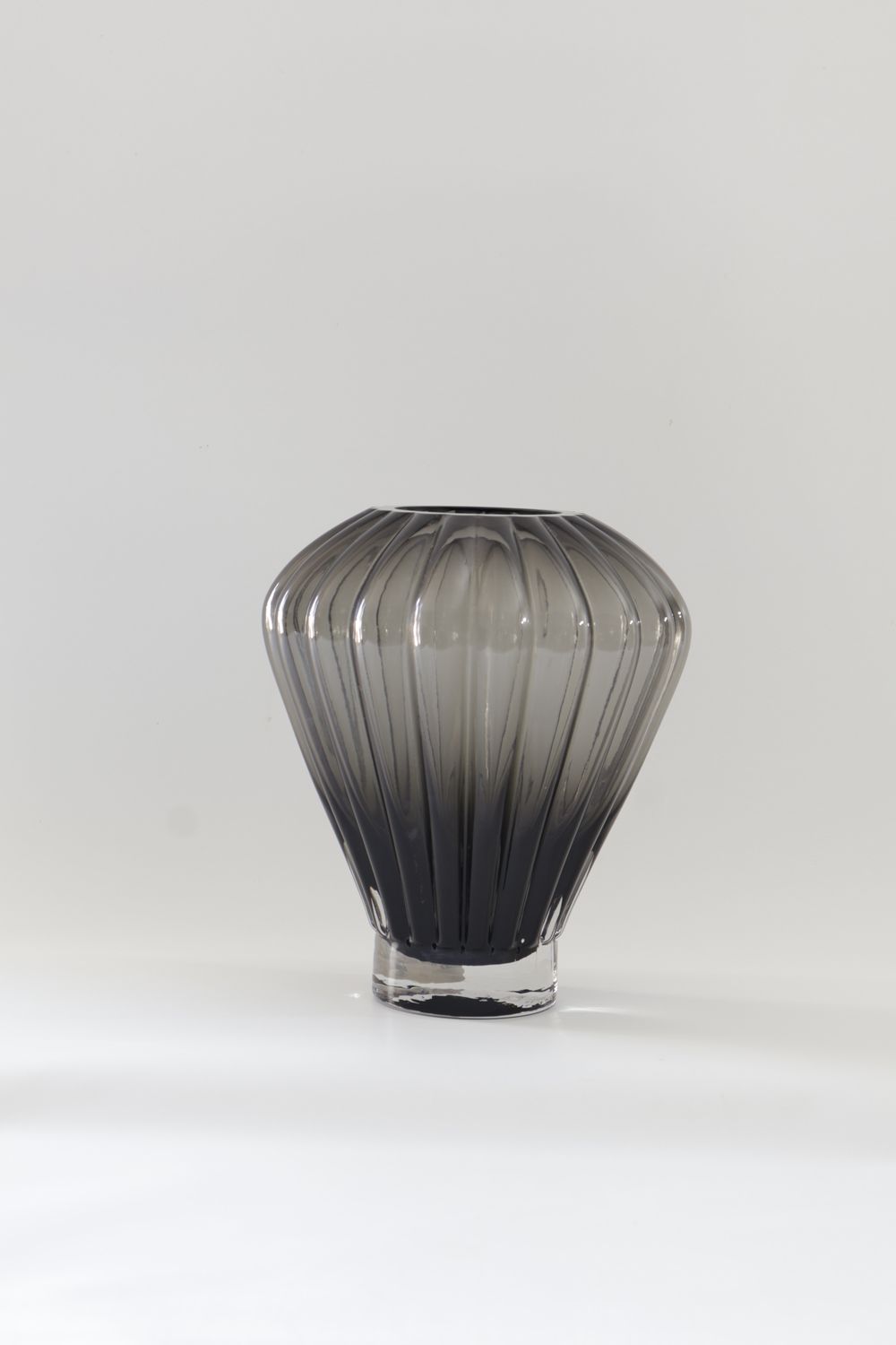 ​Smoked grey glass vase features a balloon-shaped design with ribbed vertical facets: