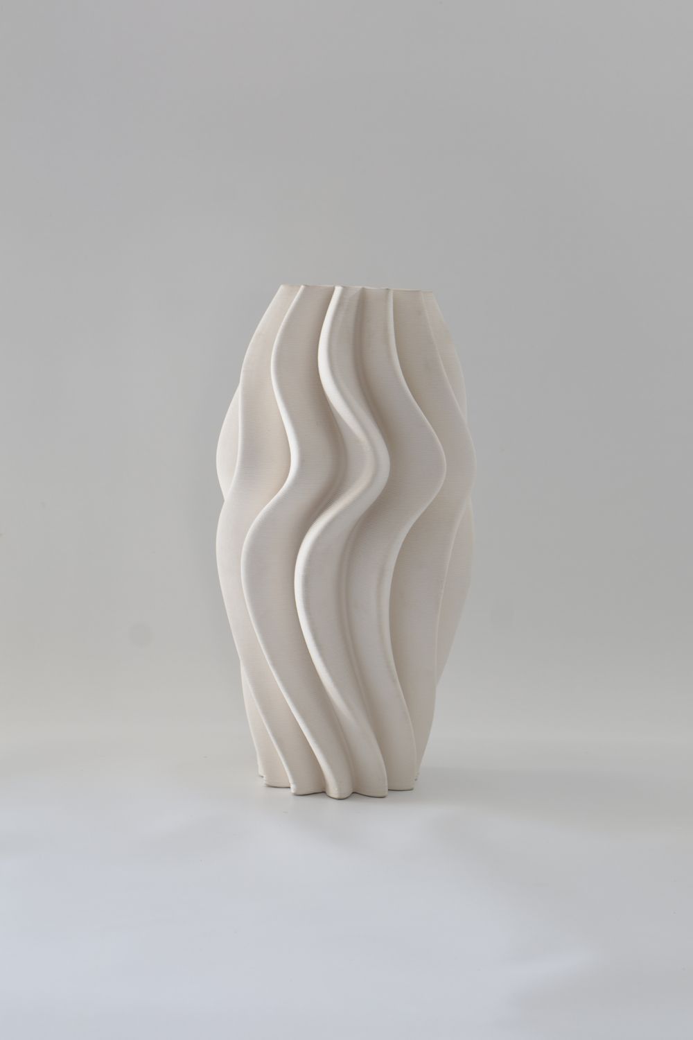 ​Off-white/light cream ceramic vase features a sculptural, organic wave design.
