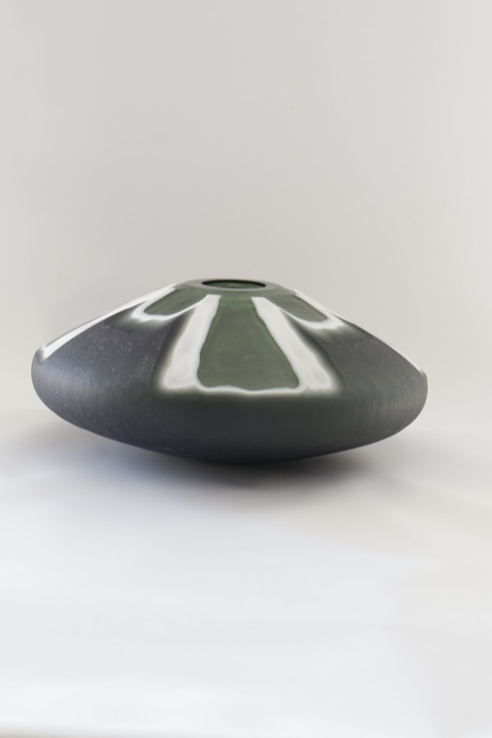 Wide, low-profile ceramic vase features a distinctive split-colour geometric design: