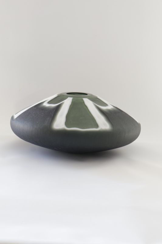 Wide, low-profile ceramic vase features a distinctive split-colour geometric design: