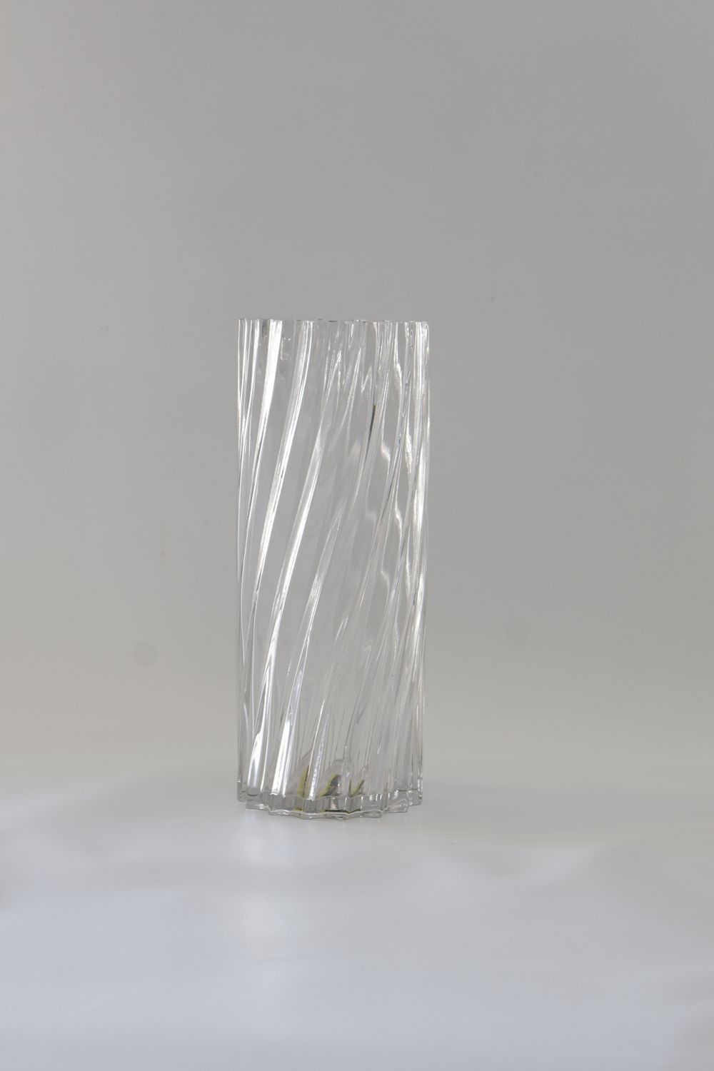 ​This vase features a tall, cylindrical twisted glass or spiral-fluted design.