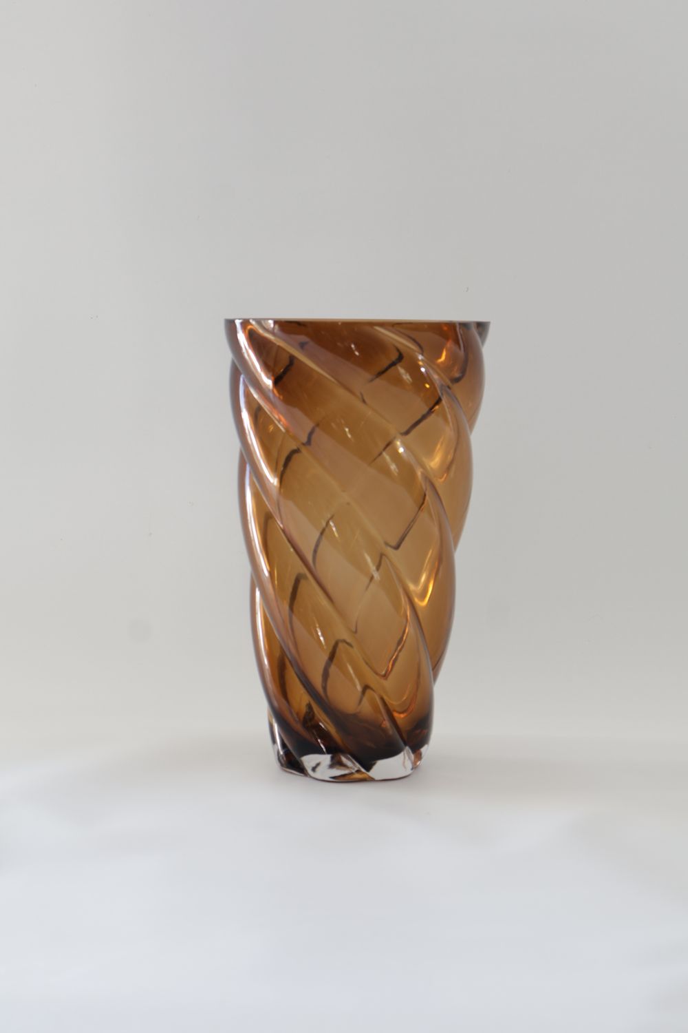 Amber/caramel glass vase features a dynamic, twisted swirl design.