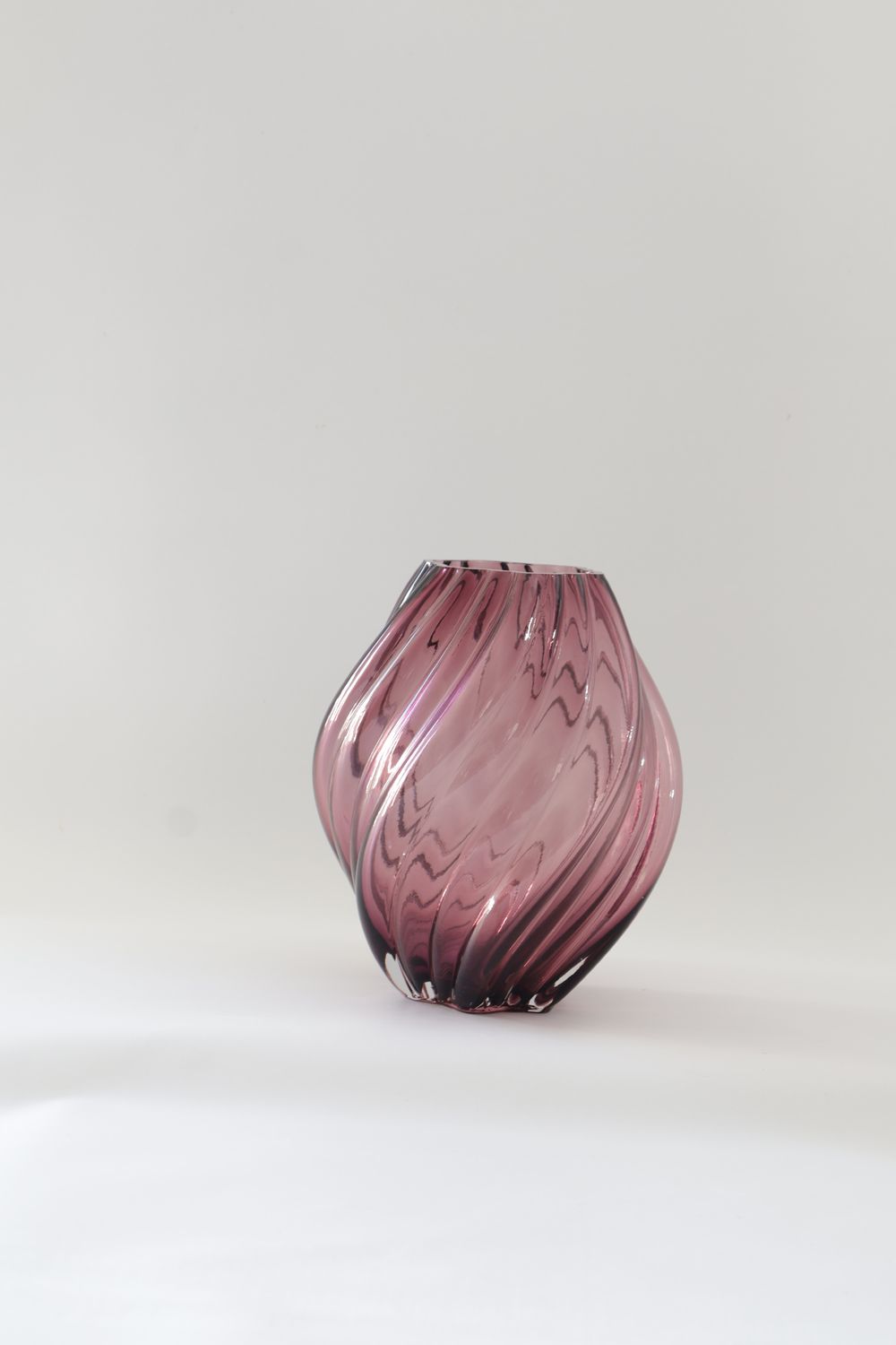 Dusky rose / mauve glass vase features a twisted, organic bulbous design