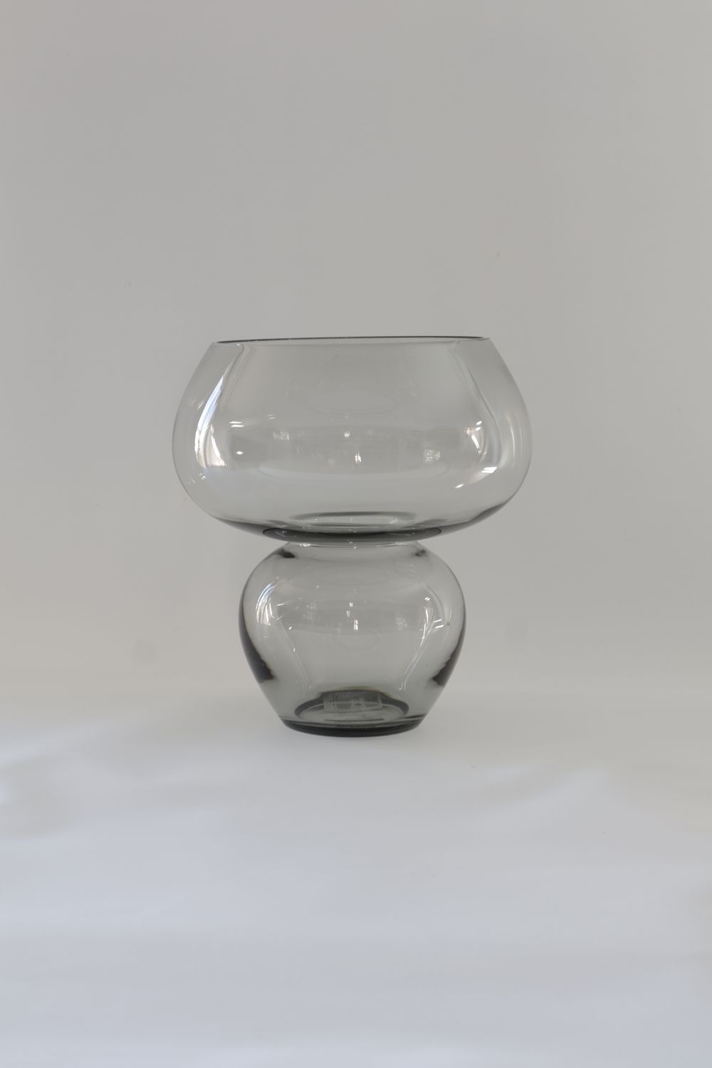 Translucent smoked glass vase features a two-tiered hourglass or mushroom-inspired silhouette