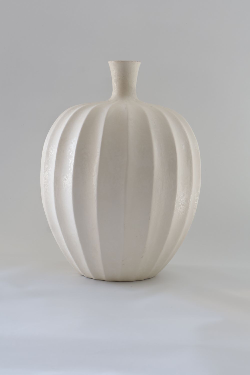 Modern pumpkin-shaped or lobed bottle silhouette with vertical ribbed fluting.