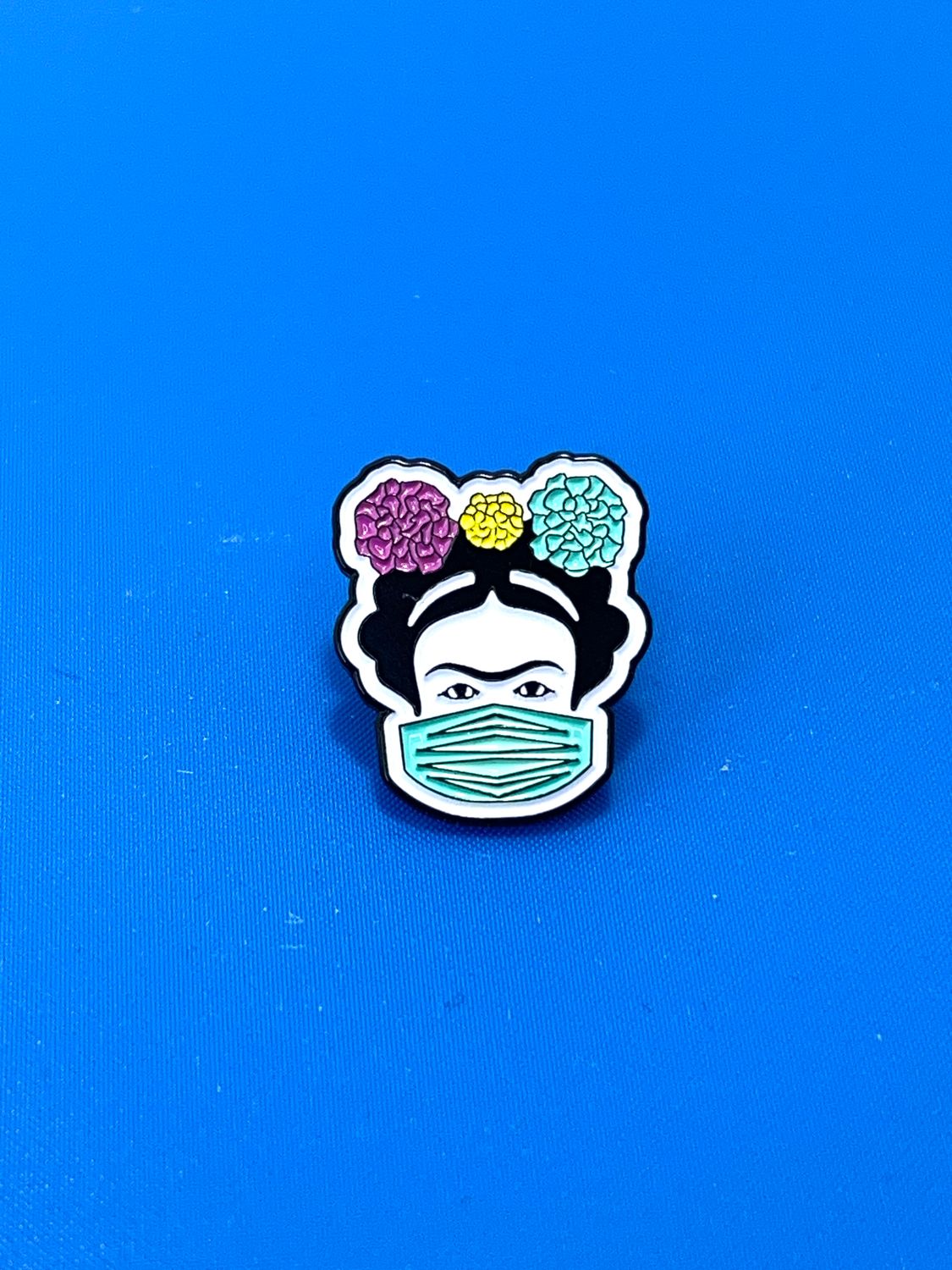Frida Metal Enamel Pin rendition of Mexican woman artist Frida Kahlo, wearing a face mask.