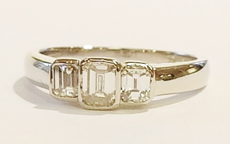 Platinum three stone emerald cut diamond ring