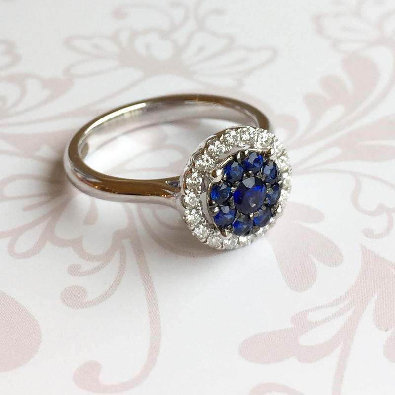 18ct white gold ring set with a brilliant sapphire cluster and a halo of brilliant cut diamonds