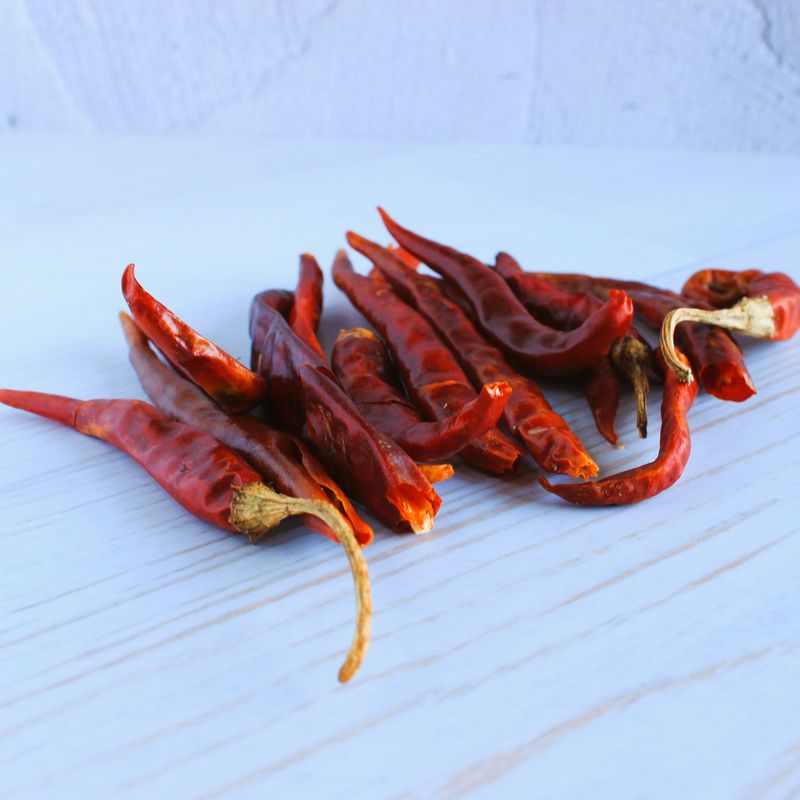 Handful of whole dried Arbol chillies on a light-coloured table
