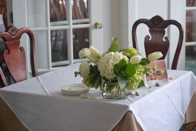 a coastal cube vase of white hydrangeas and tulips - elegant lush flowers for a wedding reception sweetheart table