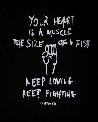 'Your Heart Is a Muscle the Size of a Fist' T-shirt Close up of the design with a fist and the words 'Your Heart Is a Muscle the Size of a Fist, Keep Loving, Keep Fighting'
