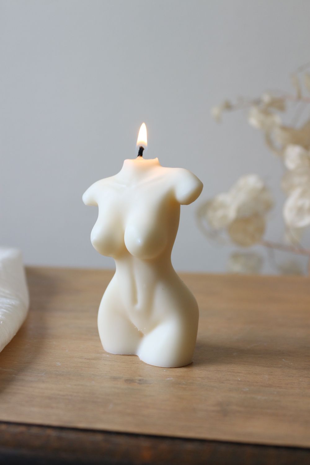 Candela in cera naturale bianca a forma di busto di donna, accesa