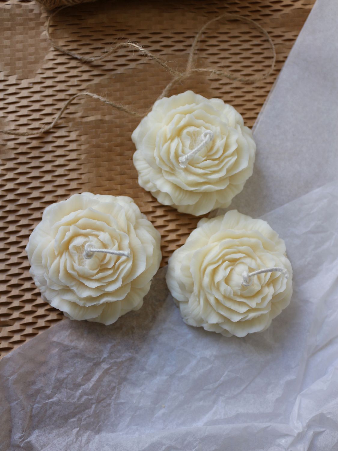 Tre candele decorative in cera naturale bianca a forma di peonia con inquadratura dall'alto