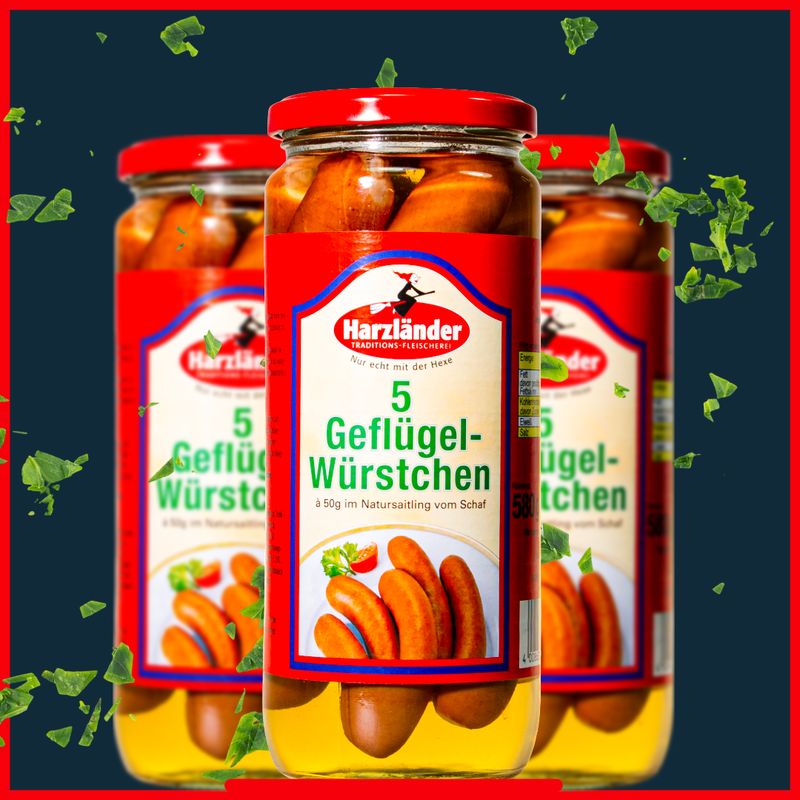 Drei Gläser Harlander Geflügel-Würstchen in roter und gelber Verpackung auf dunklem Hintergrund