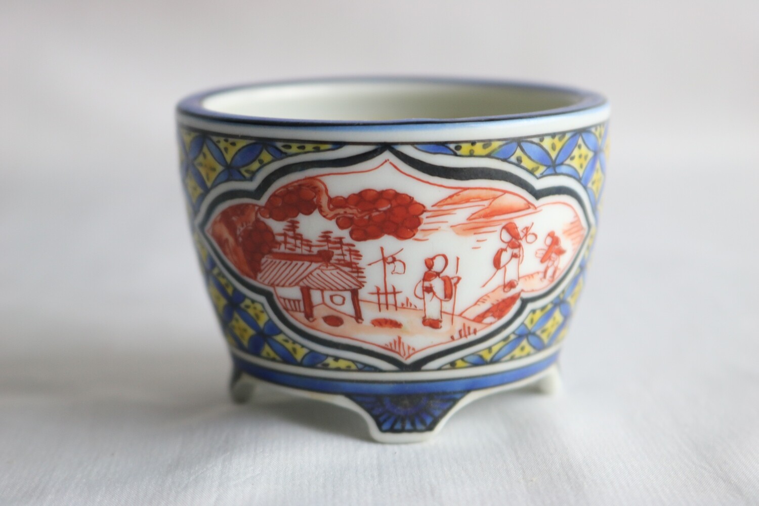 Kutani Kinsei; Japan.   6.5cm; Porcelain; Round; Akea Paintings in Mokko Windows; Kutani Geometric Patterns; Blue Rim;