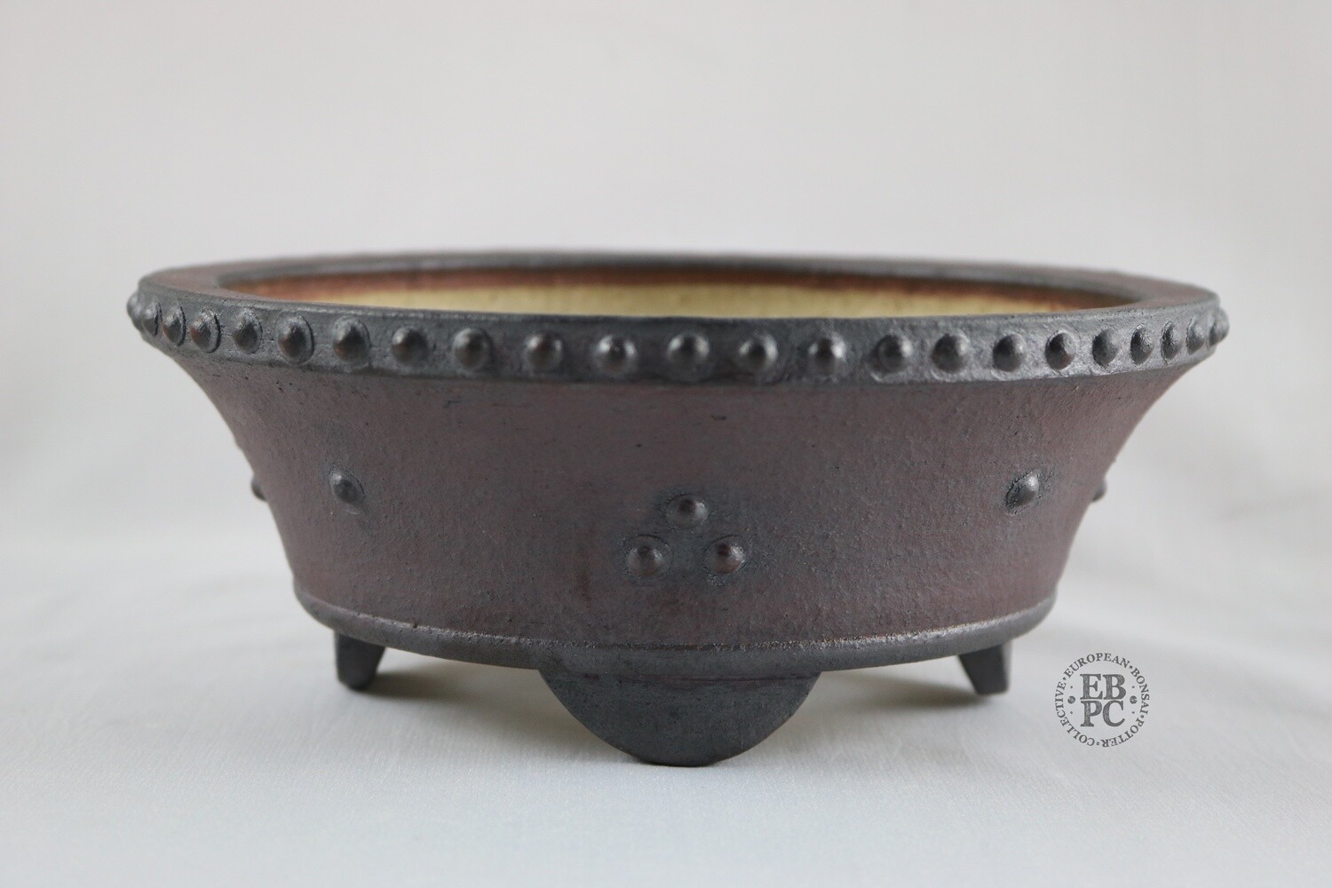 Ian Baillie - 20.5cm; Unglazed; Round; Drum Style; Formal Flared Design; Rivets/Studs; Oxides; Browns; Reddish Hues; Hand-signed; EBPC Stamped.