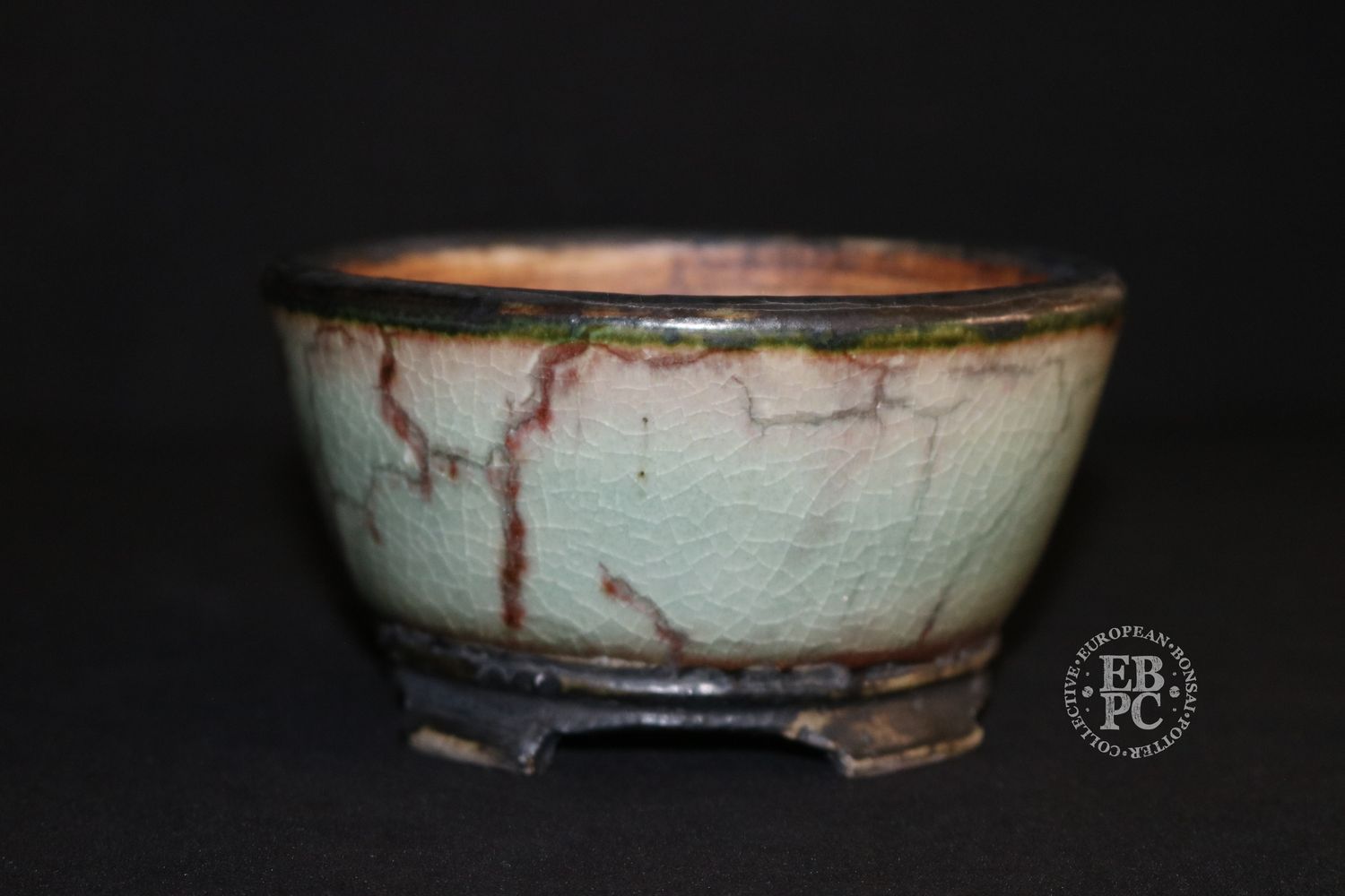 Eddie Curtis, England.   - 12.8cm; Hand-thrown; Round;  Exceptional Celadon Glaze; Blood-red Veins; Crackle Effect; Basal Band; Oxide Finished Carved Feet; Stamped with EBPC &amp; Artist&#39;s Logo.