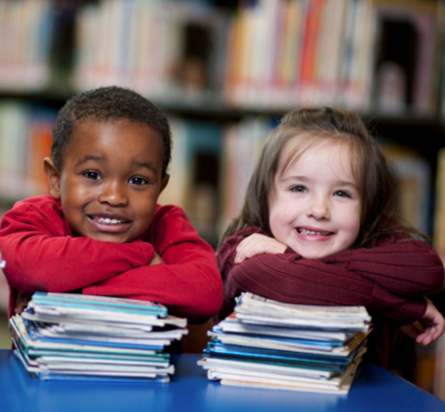 Two children each with a pile of books.
