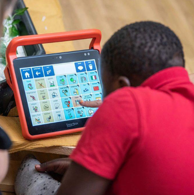 Boy using an AAC device with his teacher