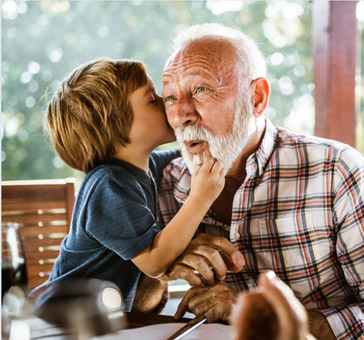 A boy is kissing his grandfather on the cheek.