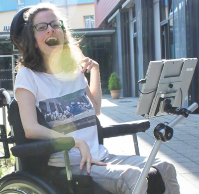 A lady in a wheelchair with her communication device mounted on an arm.