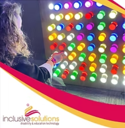 A girl sits in front of a light-up wall panel with led lights and moveable plastic pegs.