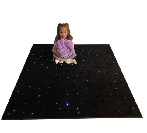 Girl sitting on a LED Sensory Fibre Optic Carpet. She is holding a Cuddle Ball.