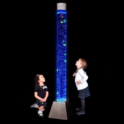 Two children looking at a tall bubble tube lit in blue