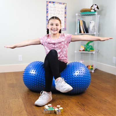 Image of child sitting on an inflatable sensory roller, facing forward