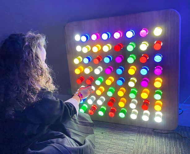 Image of child sitting in front of a wall hanging sensory light panel