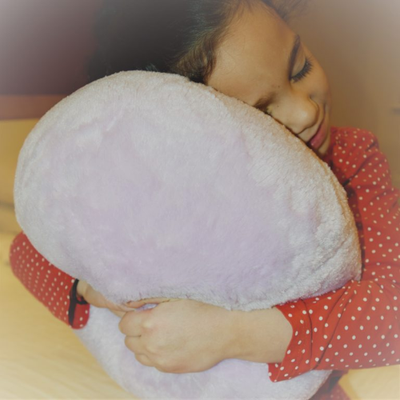 Image of a girl hugging a vibrating plush ball pillow