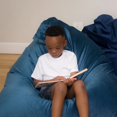 Image of a child sitting on a flip chair, reading a book