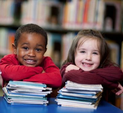 Two children each with a pile of books.