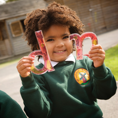 Child holding 2 letters from the set of squidgy sparkle lowercase alphabet letters