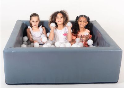 Square ball pond with white balls and 3 girls sitting inside