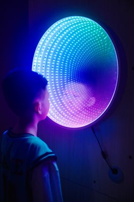 Image of a child standing in front of a lit infinity mirror