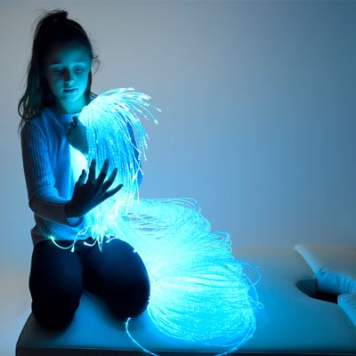 Image of girl sitting with lit fibre optic strands on her lap