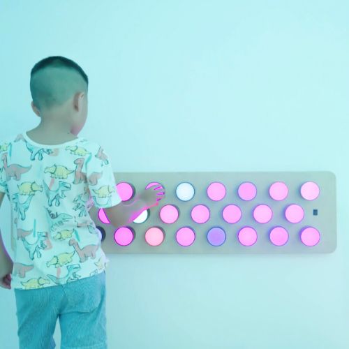 Image of child interacting with a Rotating colour spectrum light panel mounted on a wall.