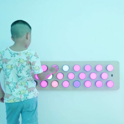 Image of child interacting with a Rotating colour spectrum light panel mounted on a wall.