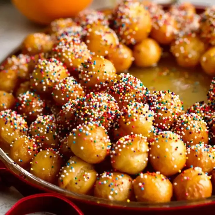 Serving suggestion: golden struffoli pastry balls coated in honey and decorated with colourful sugar sprinkles