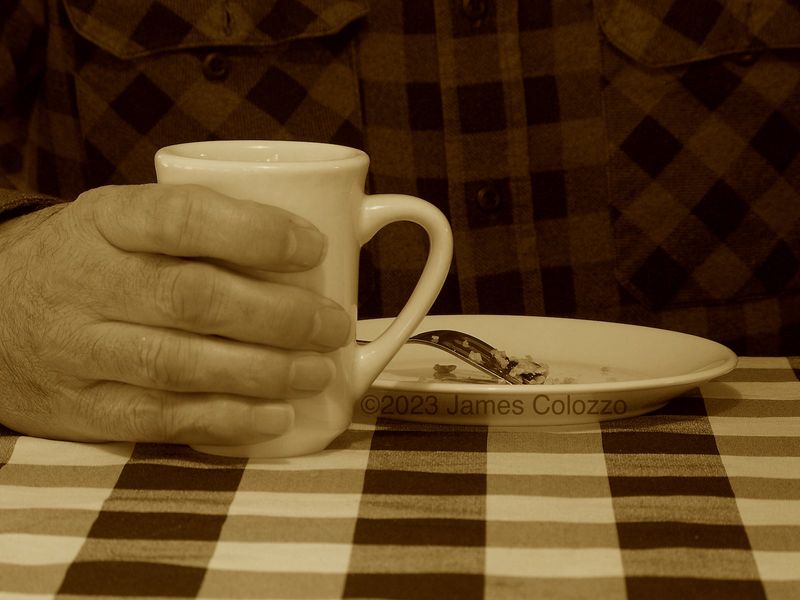 Sepia toned an old mans hand holding a coffee cup with an empty pie plate