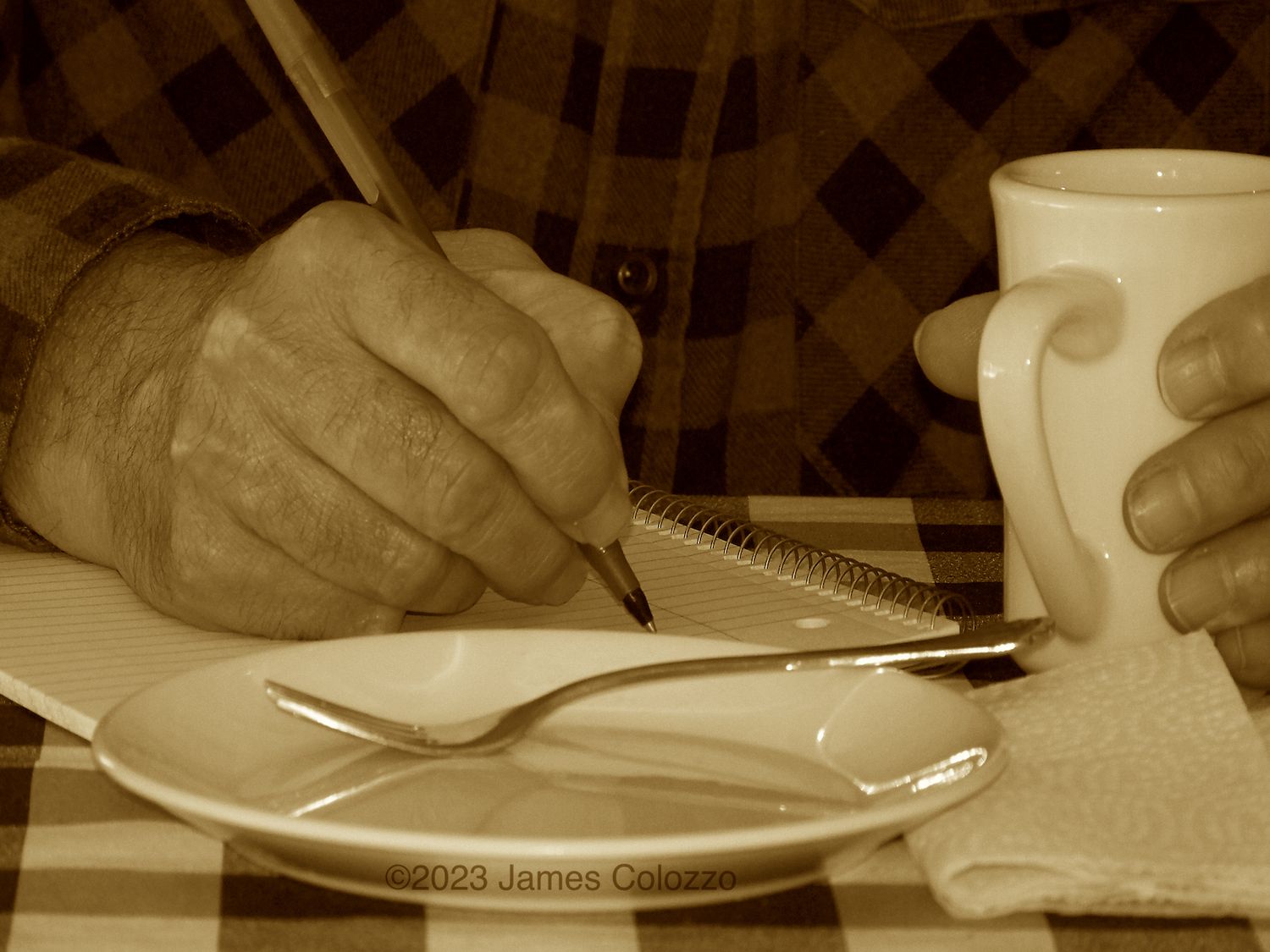 Sepia toned an old man handwriting in notebook with a coffee cup and empty pie plate