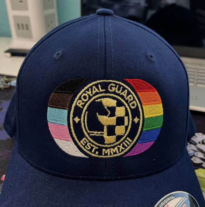 front of navy cap embroidered with Pride stripes and Royal Guard seal