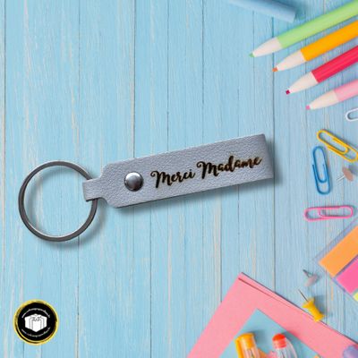 Porte-clés en cuir gris pour un cadeau de fin d'année scolaire personnalisé avec le texte merci madame. Vous pouvez aussi choisir d'indiquer uniquement votre texte.