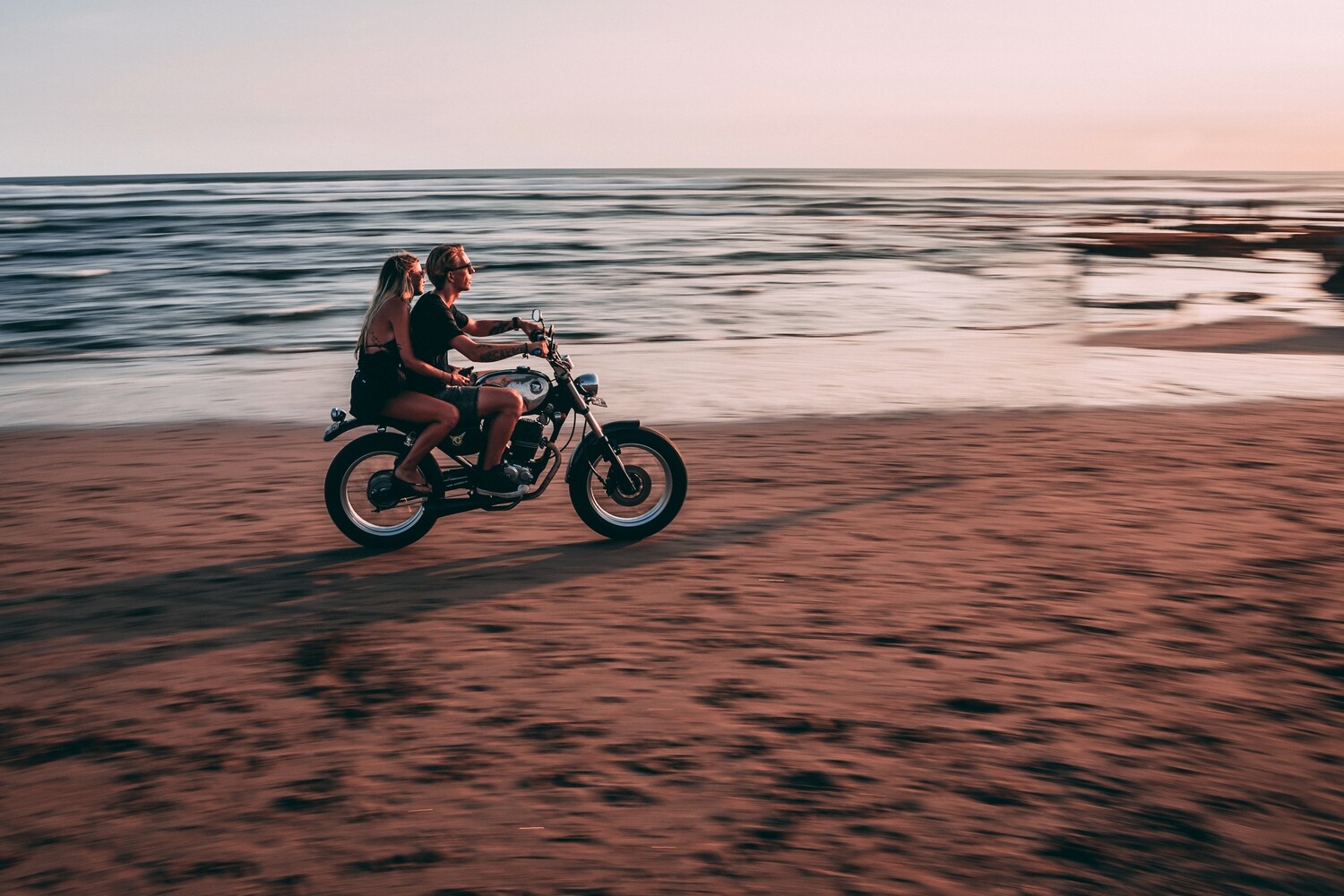 A couple riding a motorbike on the beach A couple riding a motorbike on the beach
