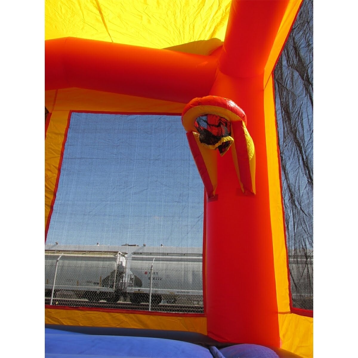 Red yellow and blue 15 by 15 jumping castle with basketball hoop in it.