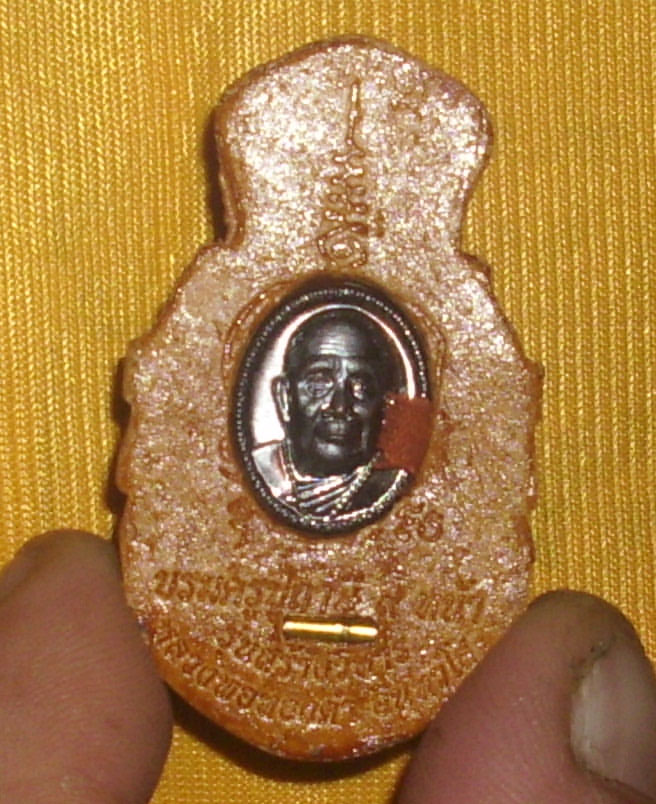 a monk coin of LP Tong Kam, and a Tagrud spell are inserted into the sacred powder mixture in the rear face of the amulet