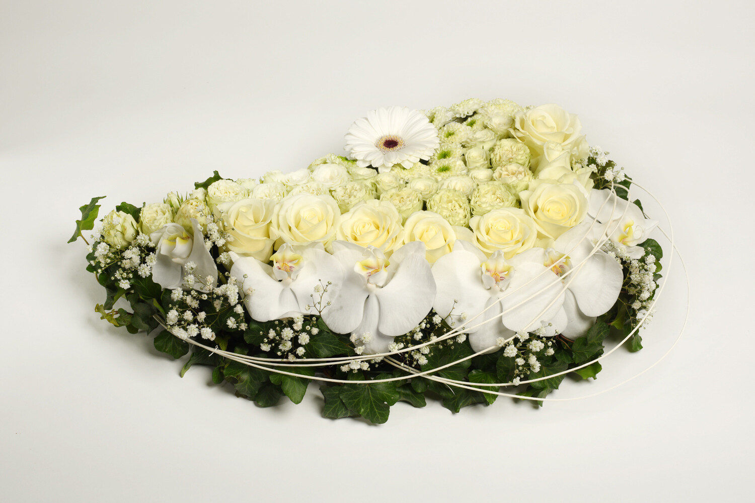 druppelvorm met witte rozen en orchideeën ong. 35 cm lang afgewerkt met klimopblaadjes.