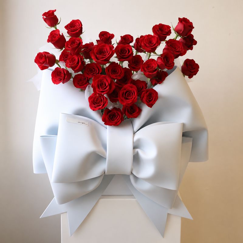 Red rose hug bucket with oversized white bow by W Floral Studio